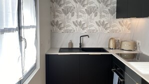 Cozinha moderna com bancada preta, pia e painel decorado com padrão floral.