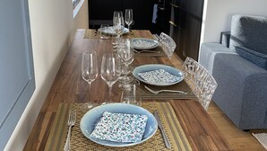 Uma sala de jantar com mesa de madeira posta para quatro pessoas, incluindo pratos, copos e talheres.