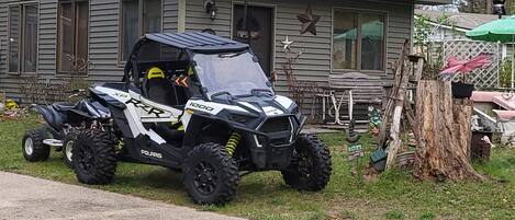 Polaris 1000 -merkkinen mönkijä on pysäköitynä talon eteen, jonka edessä on sorapäällysteinen ajotie.