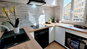 A modern kitchen with a black stove, a dishwasher, and a window with a city view. - Ze Perfect Place - Comfortable 2 Bedroom Apartment - Asc - Port - Garibaldi (Nice)