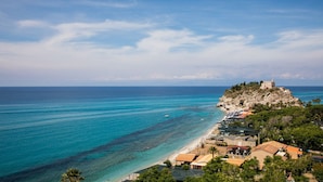 A coastal town with a beach, a castle on a hill, and clear blue waters. - Laudato Sii B&B (Tropea)