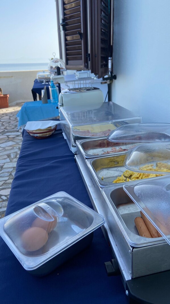 Una mesa de buffet con diferentes alimentos y vista al mar de fondo.