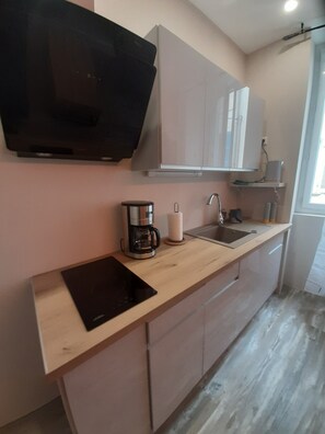 A modern kitchen with a flat-screen TV, a coffee maker, and a sink. - "Les IRIS" APT 107, T2 COSY, 30 m2, 1 bedroom with TV (Bourg-Saint-Andéol)