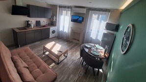 Un espacio habitable compacto con kitchenette, comedor y zona de estar.