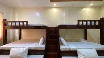 A room with bunk beds, wooden headboards, and a staircase leading to an upper level.
