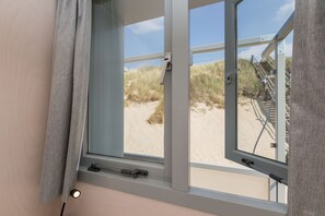 Enjoy a beach view from the large window, with access to the sandy beach via the wooden staircase.