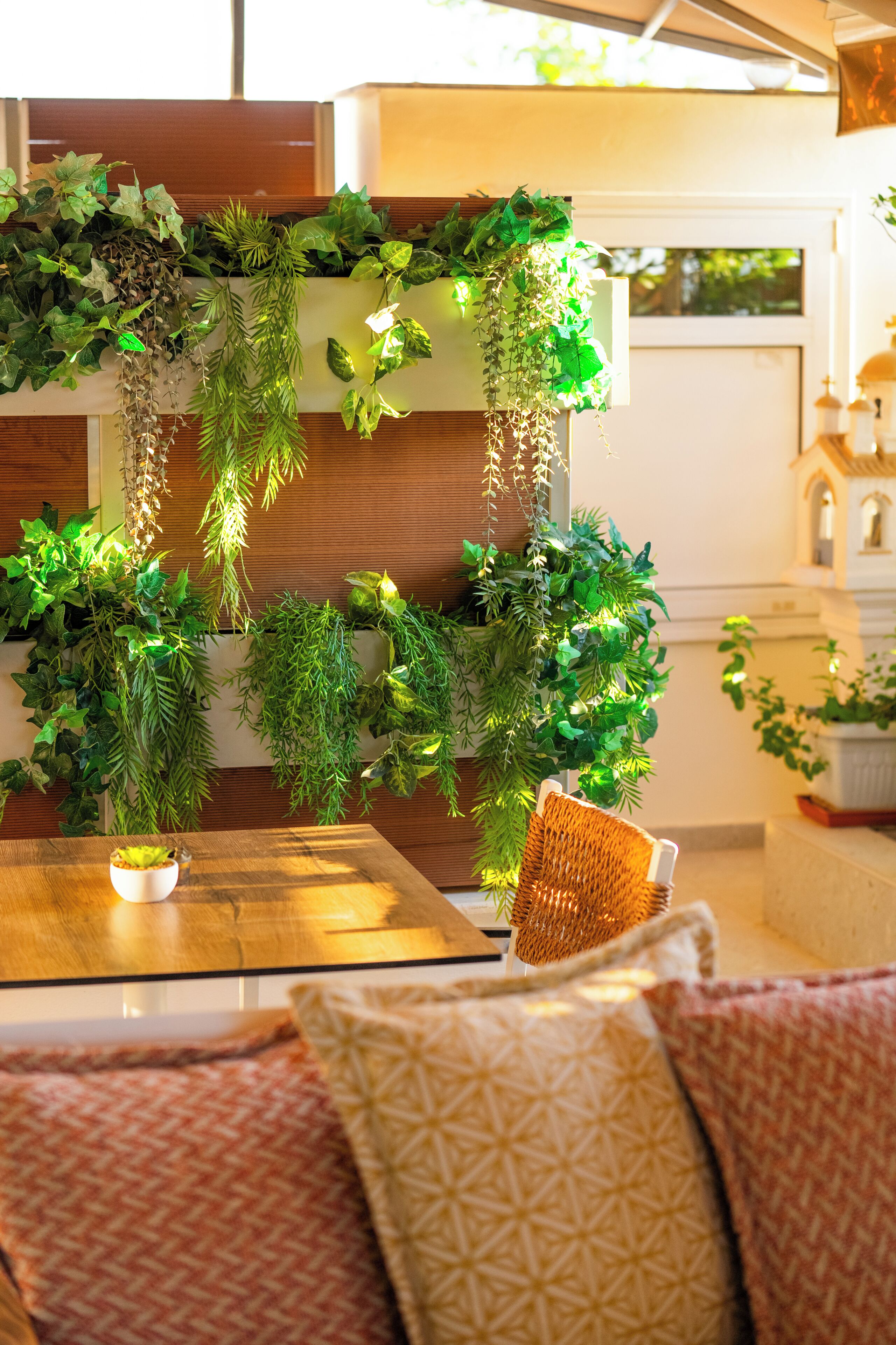Une pièce avec une table en bois, une chaise en osier et une plante suspendue.