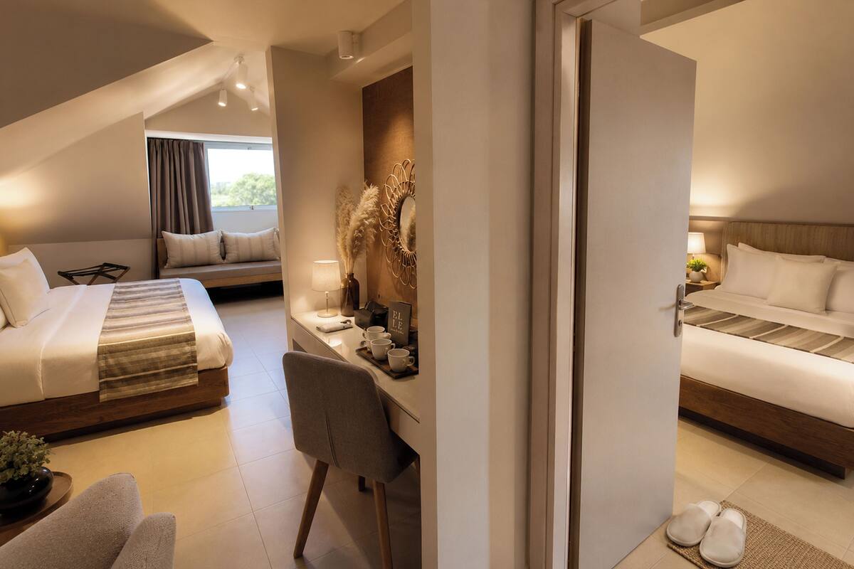 A hotel room with a bed, desk, chair, and a view of the outdoors.