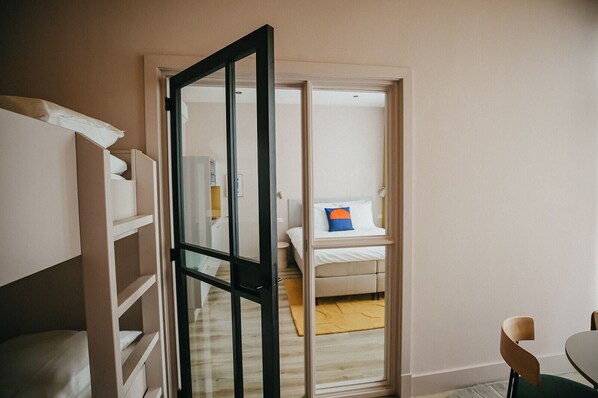 Une chambre à coucher avec un lit, une table de chevet et une fenêtre donnant sur une autre pièce.
