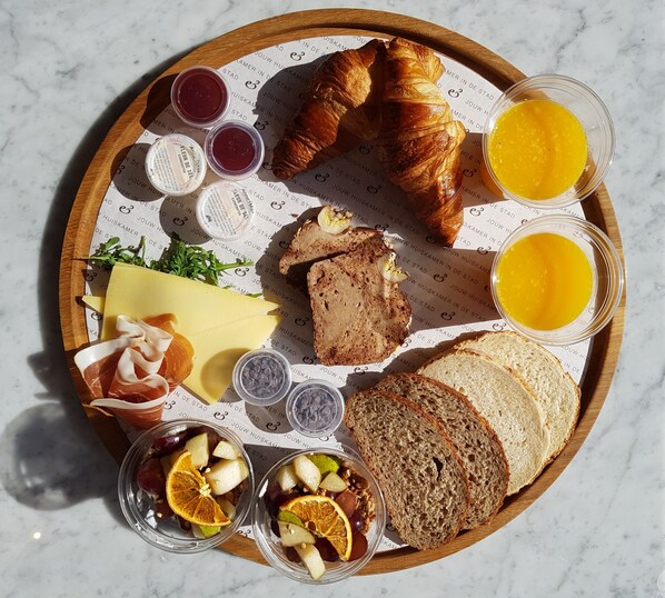 A breakfast tray with croissants, bread, cheese, fruit, and condiments. - Hotel Bries Den Haag Scheveningen (The Hague)