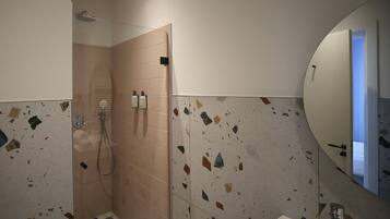 Een badkamer met een douche, een wastafel en een spiegel.