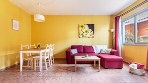 Un salon avec un canapé rouge, une table basse en bois et une table à manger avec des chaises.