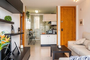 A modern living room with a sofa, a coffee table, a TV, and a dining area with a table and chairs.