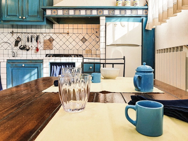 Una cocina con armarios azules, salpicadero de azulejos, estufa y refrigerador azul.