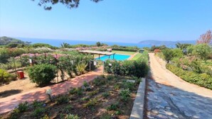 Un jardín con piscina, un camino de piedra y vistas al mar.