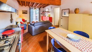 Una cocina con estufa, una mesa de comedor con sillas, un sofá y un armario rojo.