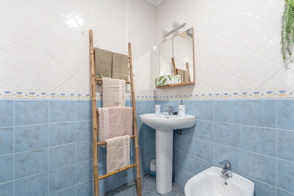 Une salle de bain avec un lavabo blanc, un miroir et une échelle en bois.