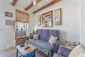 A living room with a sofa, a table with a plant, a lamp, and artwork on the walls. - Casa Don Diego: Mountain Views, Wi-Fi, and Air Conditioning (Ardales)