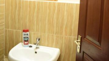 A bathroom with a white sink, a mirror with a wooden frame, and a wooden door.