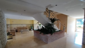 Amplia sala de estar con una escalera moderna, un conjunto de sofás y una planta grande en maceta.