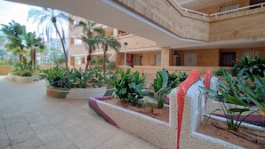 Un atrio de varios niveles con suelo de baldosas, plantas en macetas y un diseño arquitectónico moderno.