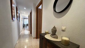 Un pasillo con un mueble de madera, una estatua de Buda y dos velas.
