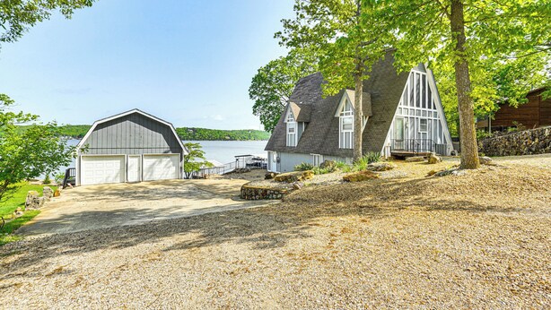 Et hus med garage, et stort træ og en grusbelagt indkørsel.