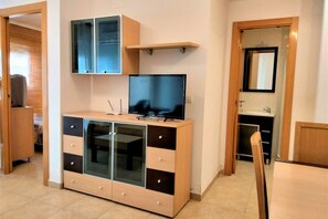 Una habitación moderna con un armario de madera, un televisor y un espejo.