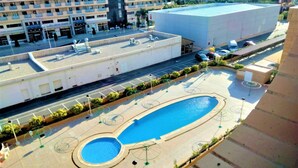 A rooftop swimming pool with a circular design, surrounded by a paved area with seating and sun loungers.