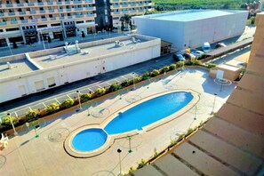 A rooftop swimming pool with a circular design, surrounded by a paved area with seating and sun loungers.