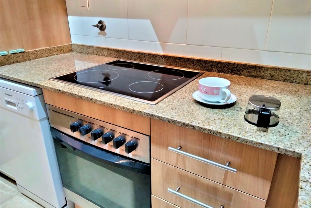 Een keuken met een inbouwfornuis, oven en koffiezetapparaat op het aanrecht.