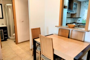 A compact kitchen with a wooden table and chairs, a small countertop, and a visible sink.