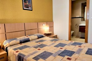 A bedroom with a bed, nightstand, and a bedside lamp.
