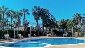Una piscina con sillones de descanso y palmeras.