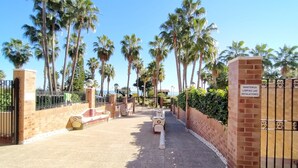 A gated entrance with palm trees, a clear sky, and a sign instructing to keep installations clean. - ACV - Acapulco I - 1ª linea planta 5 sur (Oropesa del Mar)