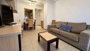 Un salon comprenant un canapé, une table basse, un téléviseur et un coin cuisine.