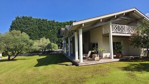 A two-story building with a covered porch, a fenced yard, and a forested backdrop. - NEW! Villa 12 persons with heated pool, 5 bedrooms, huge garden, close beach (Léon)