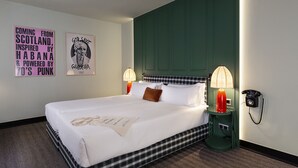 Ein Hotelzimmer mit einem großen Bett, zwei Nachttischlampen, einem Telefon und zwei Wandbildern.