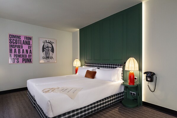 A hotel room with a large bed, two bedside lamps, a telephone, and two wall art pieces. - chic&basic Habana Hoose (Barcelona)