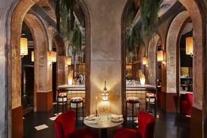 A restaurant with a central round table, red chairs, and a chandelier. - chic&basic Habana Hoose (Barcelona)