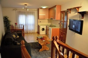 Cozy living space with a kitchenette, sofa, dining table, and TV.