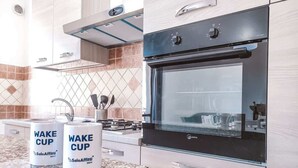 Cocina moderna con horno integrado, campana extractora de acero inoxidable y dos tazas blancas de la marca SoloAffitti sobre la encimera de granito.