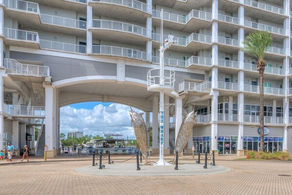 A multi-story hotel with a central atrium, a palm tree, and a sign reading "The Wharf." - The Whart Unit 505 2 Bedroom Condo by RedAwning (Orange Beach)