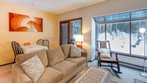 A cozy living room with a sofa, chairs, a table, and a large window with a snowy view. - 33sw - Wifi - Fireplace - Amenities - Sleeps 4 1 Bedroom Home by RedAwning (Deming)