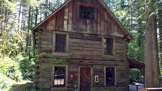 A rustic log cabin with a central door, two windows on the front, and a small porch area. - 33sw - Wifi - Fireplace - Amenities - Sleeps 4 1 Bedroom Home by RedAwning (Deming)