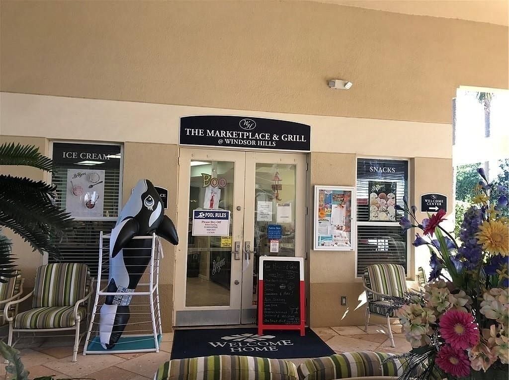 Exterior de The Marketplace & Grill en Windsor Hills, con zona de piscina, cartel de helados y felpudo de bienvenida.
