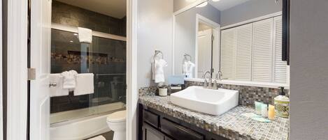 A modern bathroom with a glass-enclosed shower, a white sink, and a large mirror.