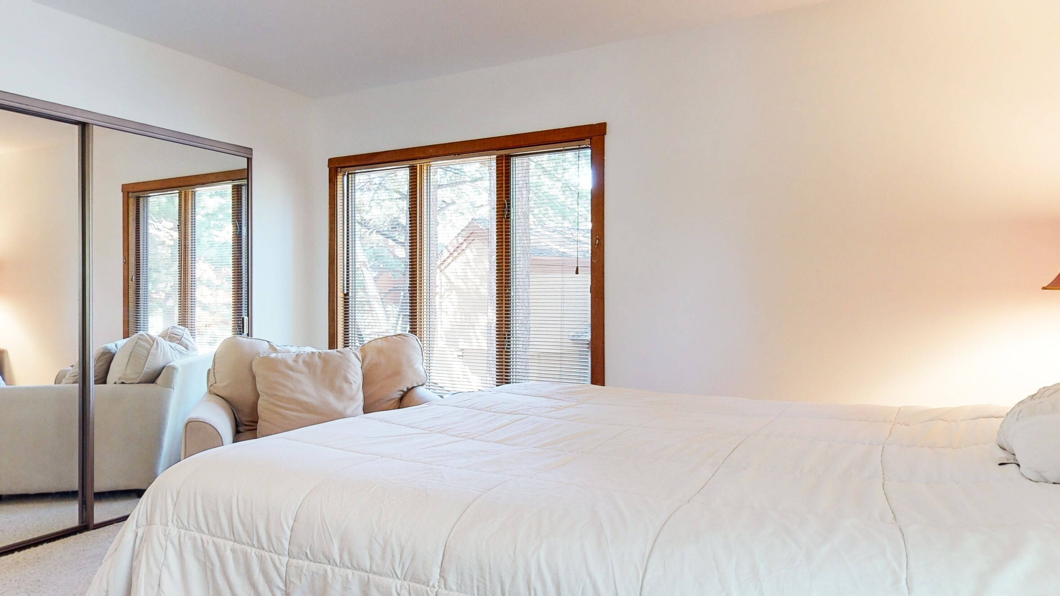 A bedroom with a large bed, a sofa, and a mirror.