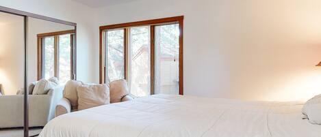 A bedroom with a large bed, a sofa, and a mirror.