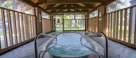 An indoor hot tub with metal railings, a concrete floor, and a wooden ceiling.